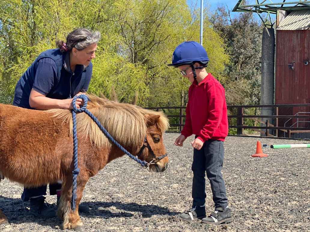 A small boy with a pony and an adult