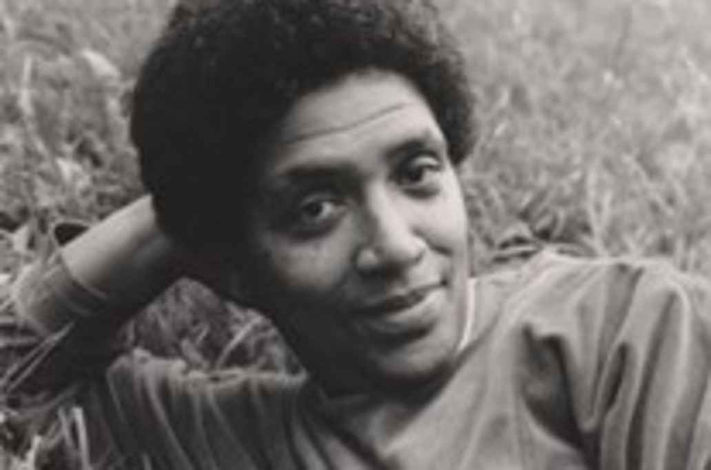 Sepia tone image of Audre Lorde reclining on grass