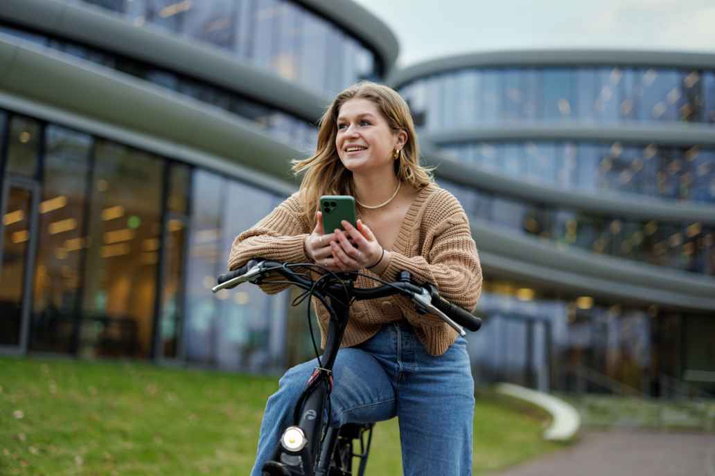 A woman stopped on a bike holding a mobile phone